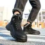 Hiker wearing black waterproof boots on forest trail.
